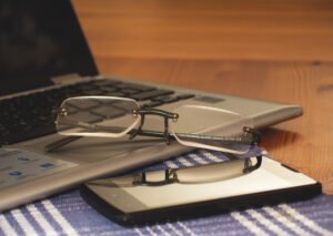 Computador, óculos e telefone em mesa de trabalho; foto de arquivo de 2017. Não registra instalações ou alunos da Enap.