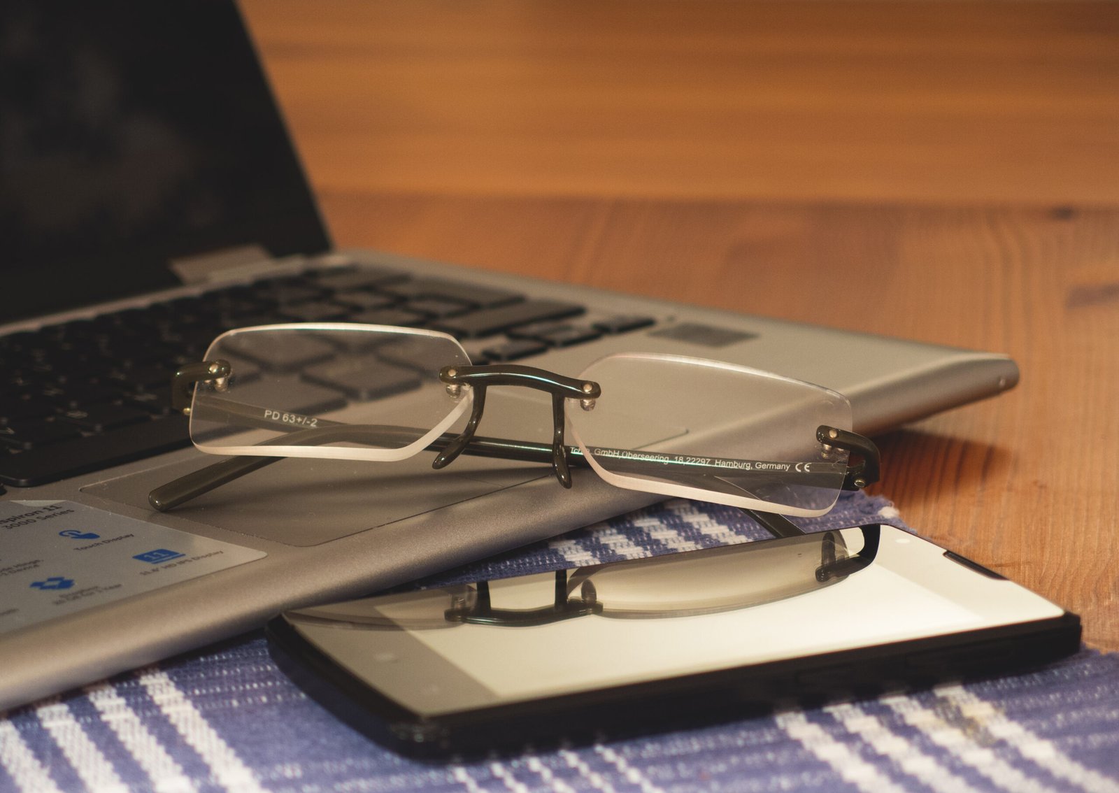 Computador, óculos e telefone em mesa de trabalho; foto de arquivo de 2017. Não registra instalações ou alunos da Enap.