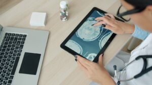 Fotografia de contexto: mãos sobre tablet com imagens cerebrais; não mostra implante ou participantes da Neuralink.