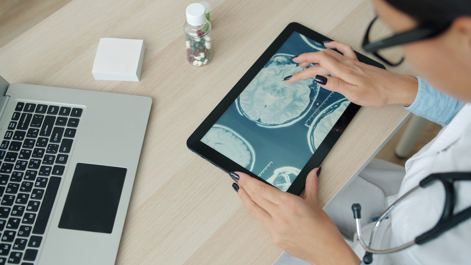 Fotografia de contexto: mãos sobre tablet com imagens cerebrais; não mostra implante ou participantes da Neuralink.